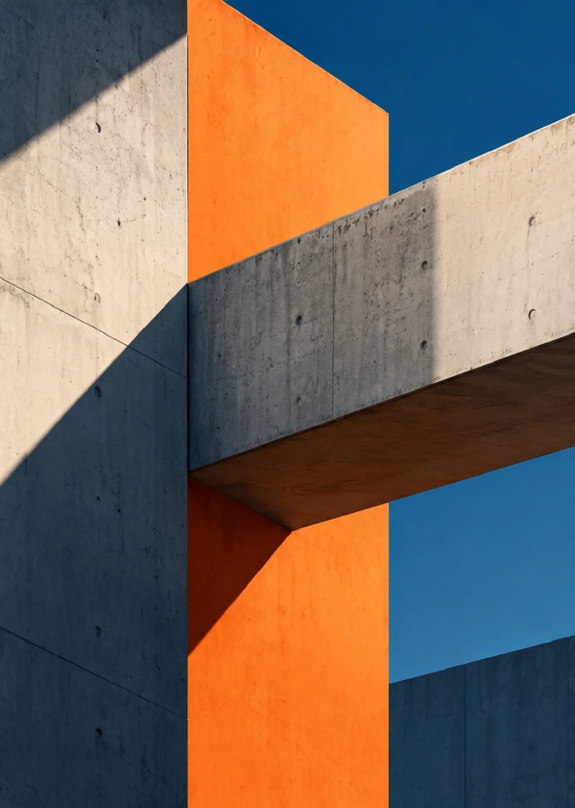 Colonne orange entre des volumes de béton, sous un ciel bleu